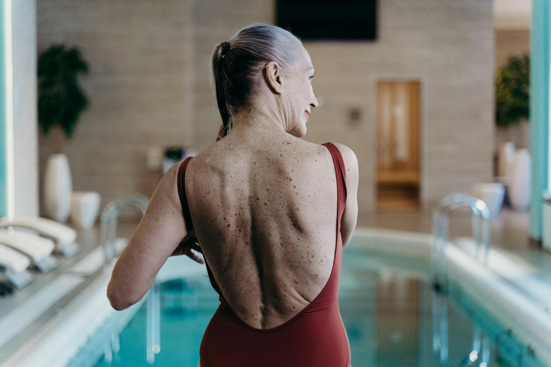A woman in a swimsuit beside an indoor pool