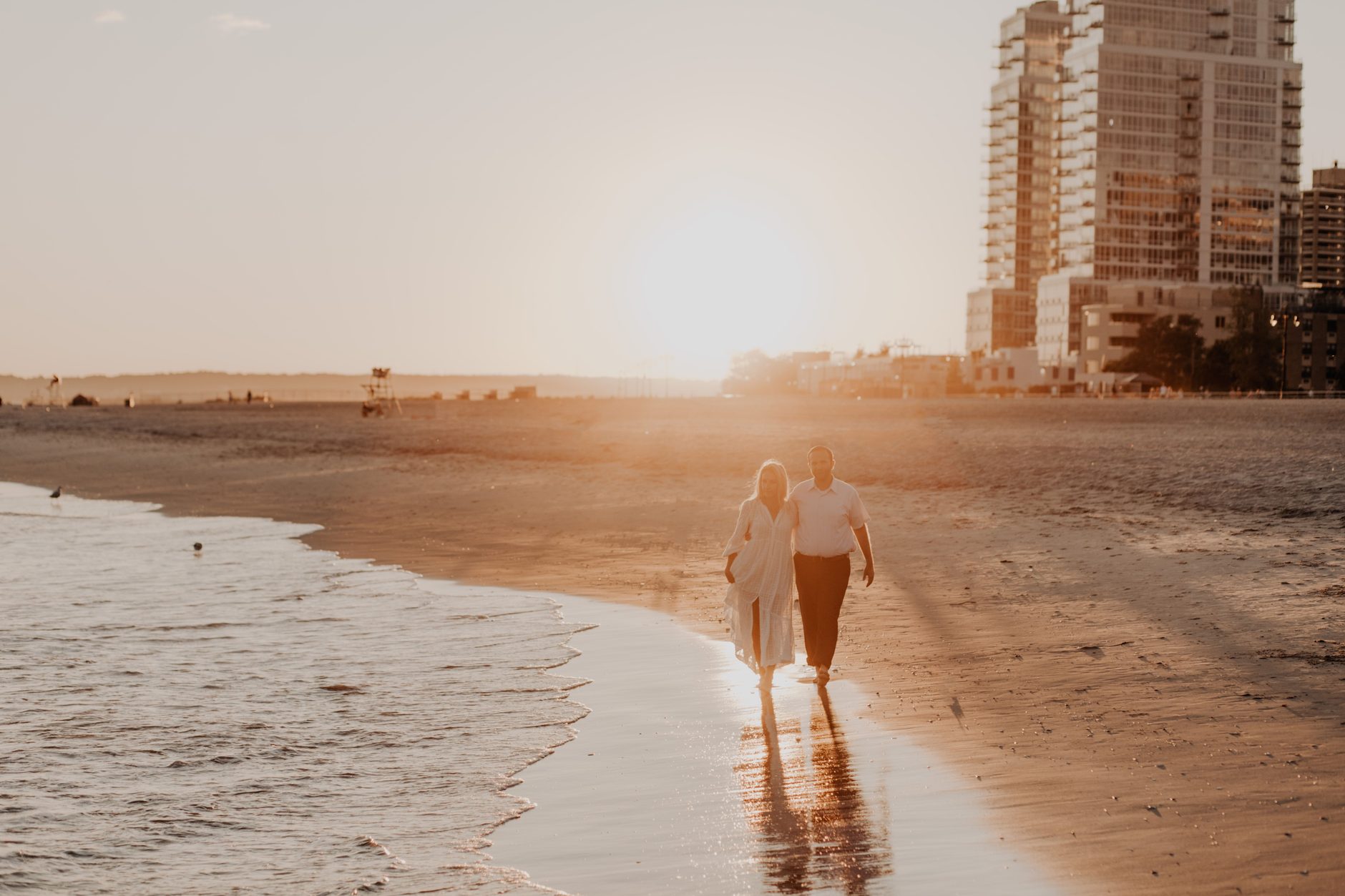 A couple walking along the shoreline at sunset