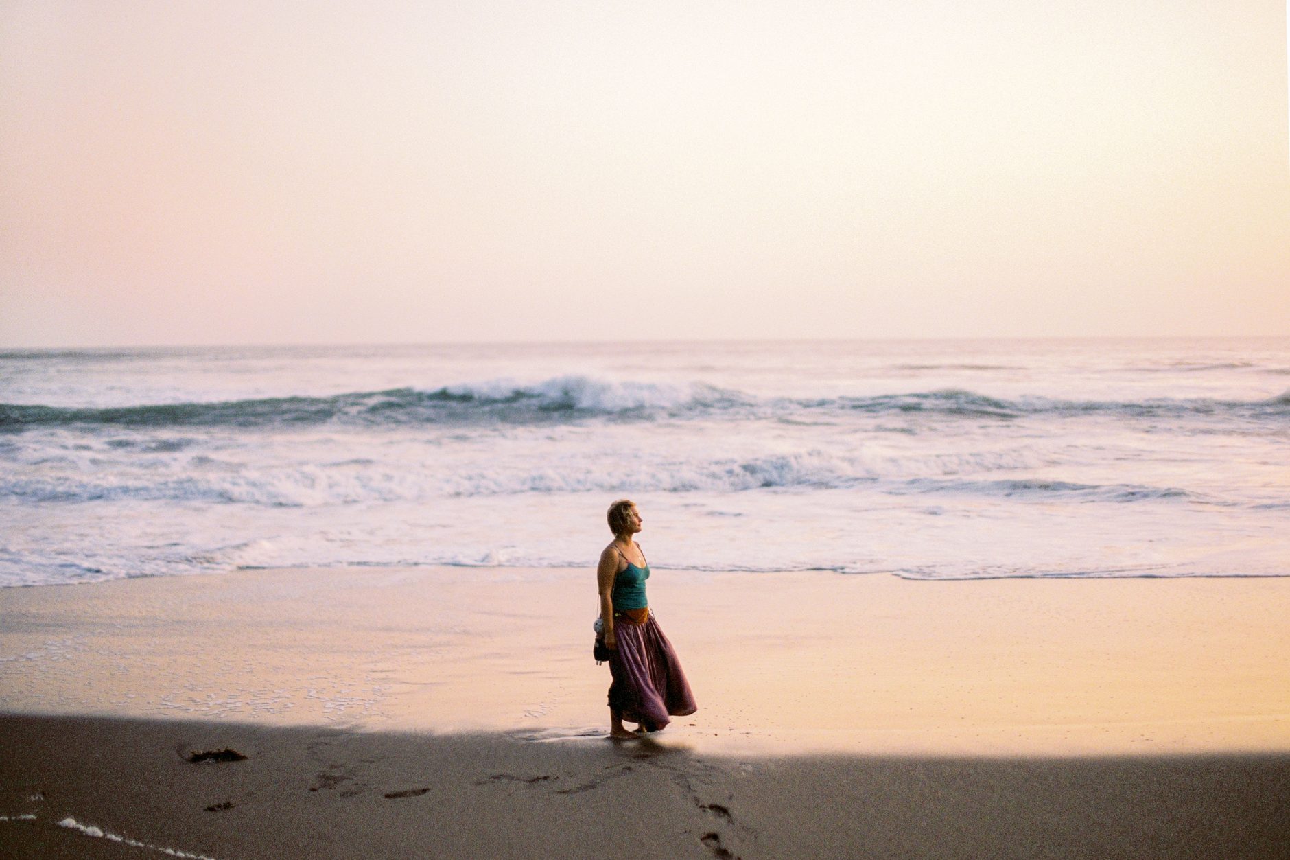 A woman walking along the shore at sunrise