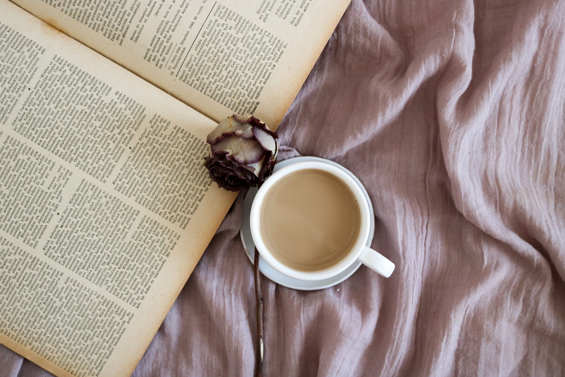An open book and a cup of coffee on linen