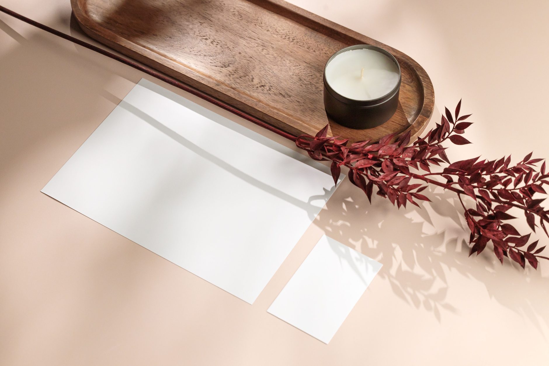A lit candle and dried flowers on a wooden tray