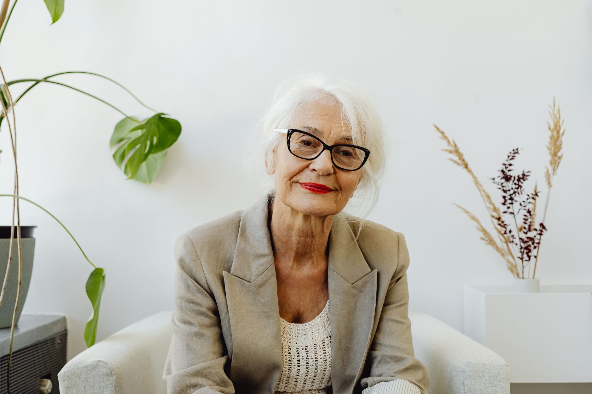 A woman seated in a bright, plant-filled room